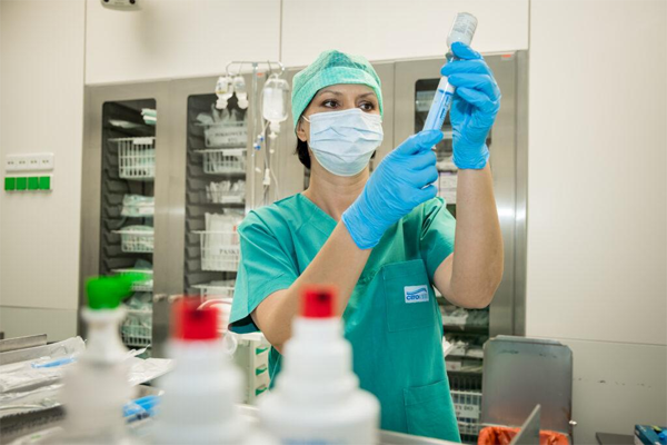Nurse preparing an intramuscular injection while following aseptic infection control practices.
