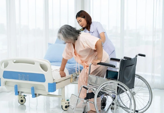 Nurse assisting patient transfer from bed to wheelchair safely