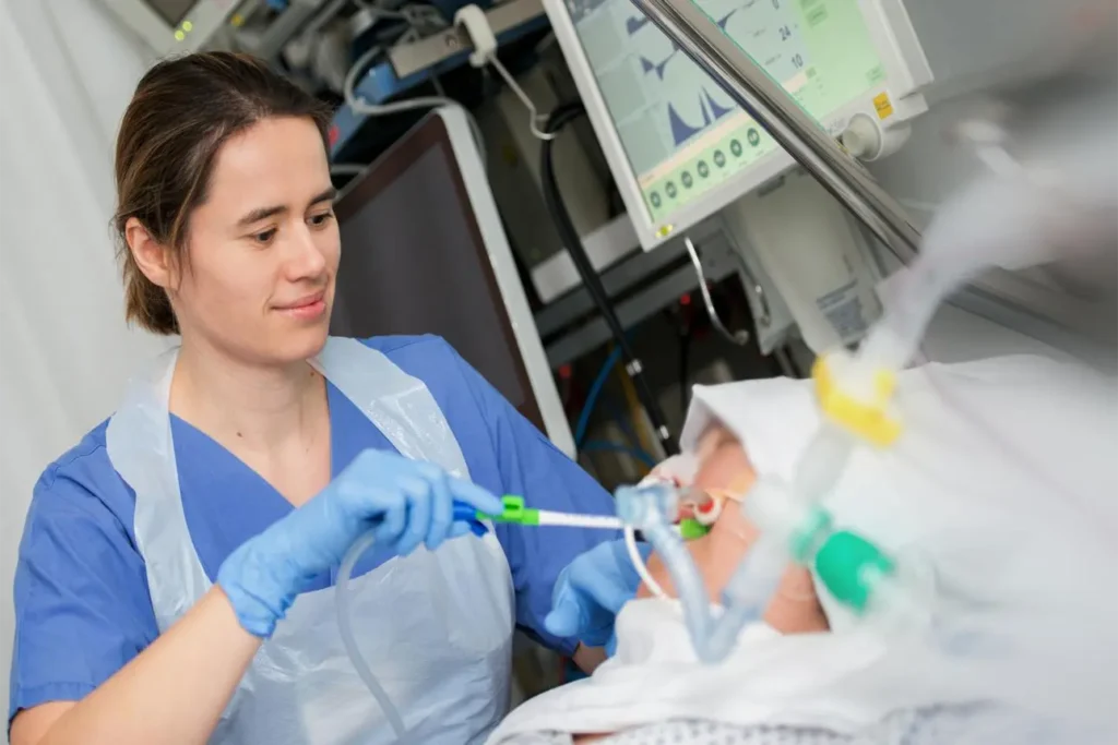 Critical care nurse performing endotracheal tube suctioning on an intubated ICU patient