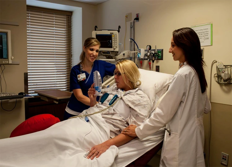 Nurse teaching a postoperative patient deep breathing exercises during recovery
