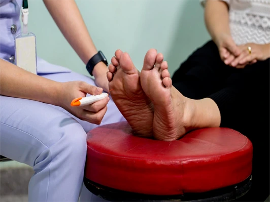 Nurse examining a patient's feet during a diabetic foot care assessment