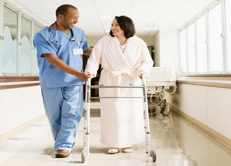 Nurse helping a postoperative patient safely stand and walk during early recovery